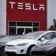 A row of Tesla cars sit outside a dealership.